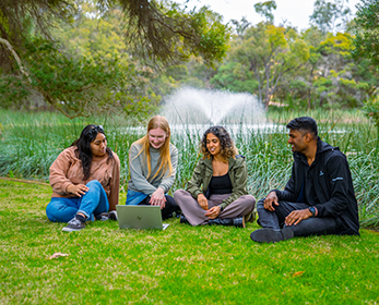 ECU students at lake looking at a laptop