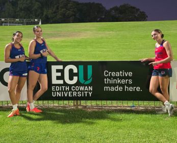 Three West Perth WAFLW players standing with an ECU barrier banner.