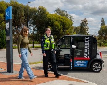 A student walks with an ECU Security Officer next to a campus security vehicle, highlighting safety services on campus.